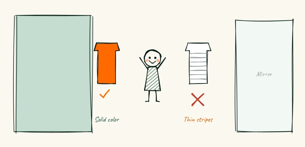 Wear your own advice A doodle photographer holding up two tops beside a backdrop and a mirror, a solid orange one with a tick labeled solid color and a striped one with a cross labeled thin stripes