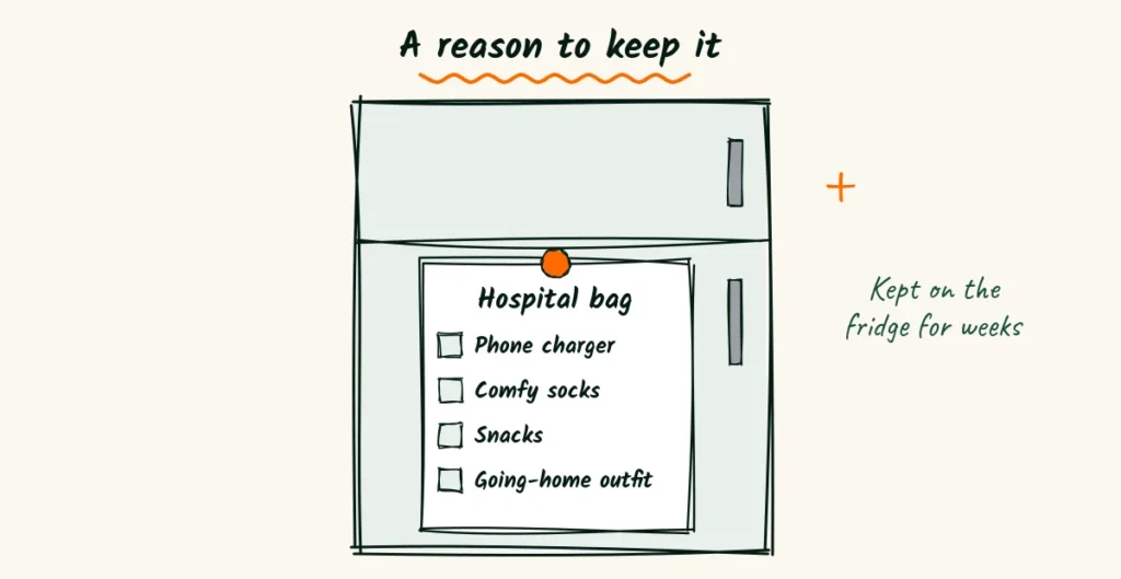 A newborn flyer flipped to its back showing a hospital bag checklist with a phone charger, socks, snacks and a going-home outfit, stuck on a fridge