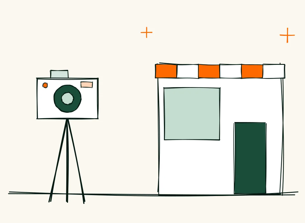 A camera on a tripod facing a small shop front with a striped awning