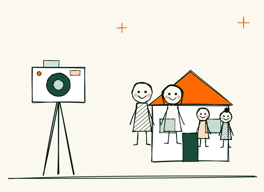 A camera on a tripod facing a smiling family of four in front of their home